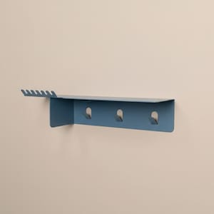 Pu&ograve; includere: Una mensola da parete in metallo blu opaco con una superficie superiore piatta, tre ganci integrati sul pannello frontale e un'estensione laterale con sei piccole tacche progettate per appendere oggetti. La struttura &egrave; solida e rettangolare.