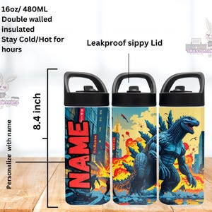 May include: A set of three insulated water bottles with black lids and handles. Each bottle features a unique design: one with the name "NAME" in red, and the others with a Godzilla theme. The bottles are 8.4 inches tall and hold 16oz (480ml).