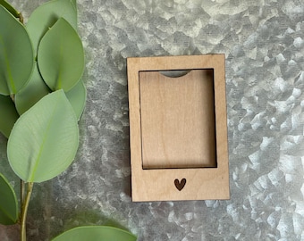 May include: A wooden picture frame with a heart cutout at the bottom. The frame is light brown and has a natural wood finish.