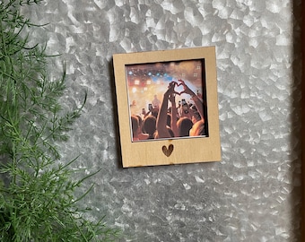 May include: A wooden photo frame with a heart-shaped cutout in the bottom center. The frame holds a photo of a crowd of people at a concert, with their hands raised in the air.