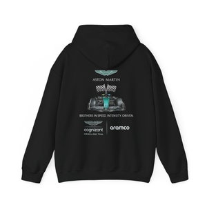 May include: Black hooded sweatshirt with a green and white Formula One race car graphic, the Aston Martin logo, and the text "ASTON MARTIN", "BROTHERS IN SPEED. INTENSITY, DRIVEN.", "cognizant FORMULA ONE TEAM", and "aramco".