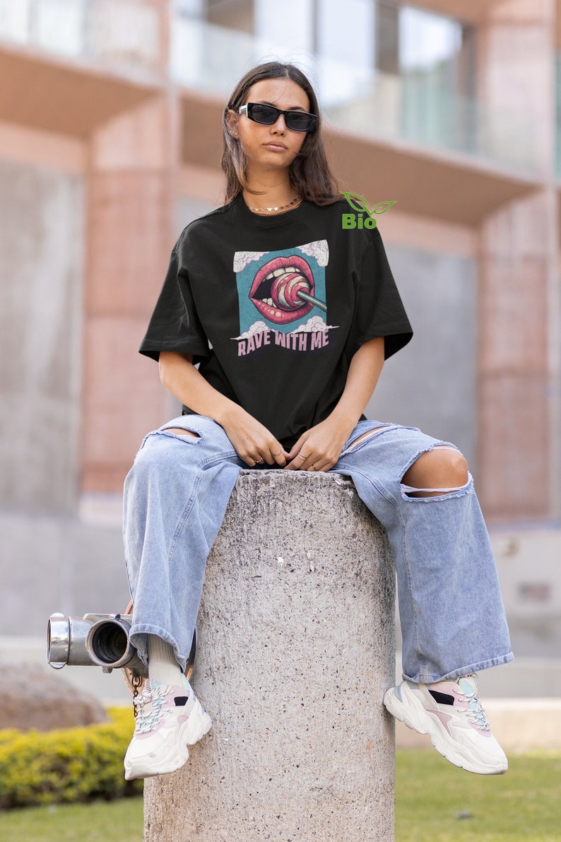 May include: Black t-shirt featuring a graphic of a mouth with a lollipop and the text "Rave With Me" printed on it.
