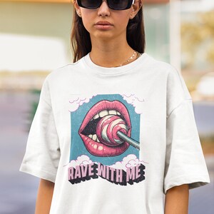 May include: White t-shirt featuring a graphic of a pink mouth with a lollipop and the text "Rave With Me" in pink and black lettering.