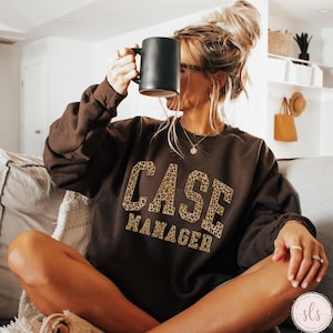 May include: A brown sweatshirt with the words "CASE MANAGER" printed in leopard print on the front.