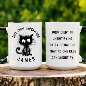 May include: White ceramic mug with a black handle. The mug features a black cat illustration and the text "Shit Show Supervisor James". The other side of the mug has the text "Proficient in Unshitifying Shitty Situations That No One Else Can Unshitify."
