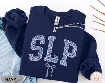 May include: Navy blue sweatshirt with a white floral pattern spelling out "SLP" and a white bow.