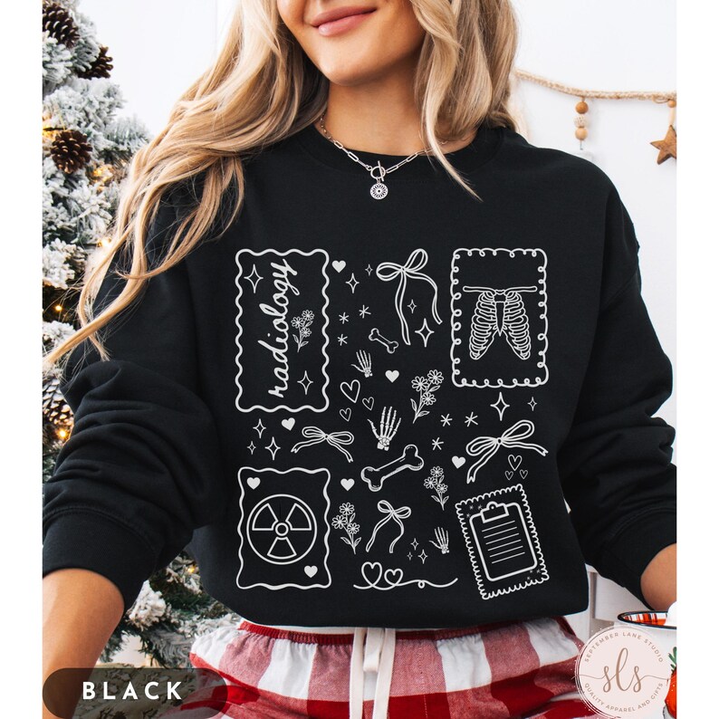 Puede incluir: Sudadera negra con dise&ntilde;os gr&aacute;ficos blancos relacionados con la radiolog&iacute;a. El dise&ntilde;o incluye la palabra "radiology", huesos, corazones, lazos, flores y una imagen de rayos X. La esquina inferior izquierda de la sudadera dice "BLACK".