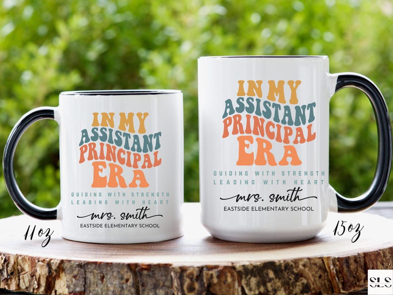 May include: Two white ceramic coffee mugs with black handles. The mugs have a colorful retro design with the text "In My Assistant Principal Era" and "Guiding with Strength Leading with Heart". The text also includes the name "mrs. smith" and "Eastside Elementary School". The mugs are 11 oz and 15 oz.