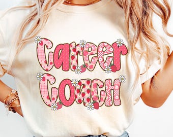 May include: Ivory t-shirt featuring the words "Career Coach" in a pink, strawberry, and daisy design. The text is outlined in a darker pink and has a playful font. The shirt is made of a soft material.