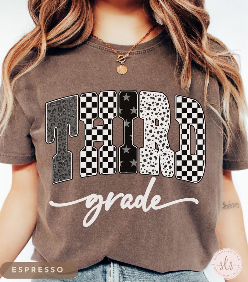May include: Espresso-colored t-shirt with the words "THIRD grade" in a bold, decorative font. The letters feature various patterns, including leopard print, checkered, and star designs. The word "grade" is written in a cursive script.