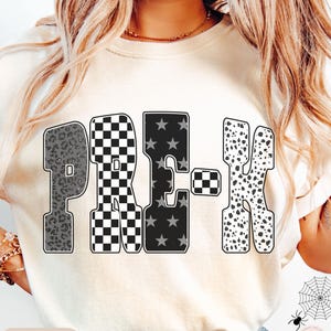 May include: Ivory-colored sweatshirt featuring the word "PRE-K" in a bold, decorative font. The letters have unique patterns: leopard print, checkered, star-filled, and dalmatian spots. The word "IVORY" is printed at the bottom.