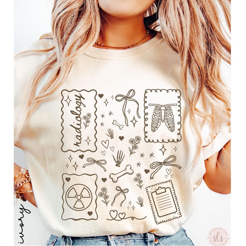 Puede incluir: Camiseta de color marfil con ilustraciones de tem&aacute;tica m&eacute;dica. El dise&ntilde;o incluye la palabra "radiolog&iacute;a" en un marco decorativo, junto con im&aacute;genes de huesos, una caja tor&aacute;cica, un s&iacute;mbolo de radiaci&oacute;n, lazos, corazones y una carpeta. La camiseta tiene cuello redondo.