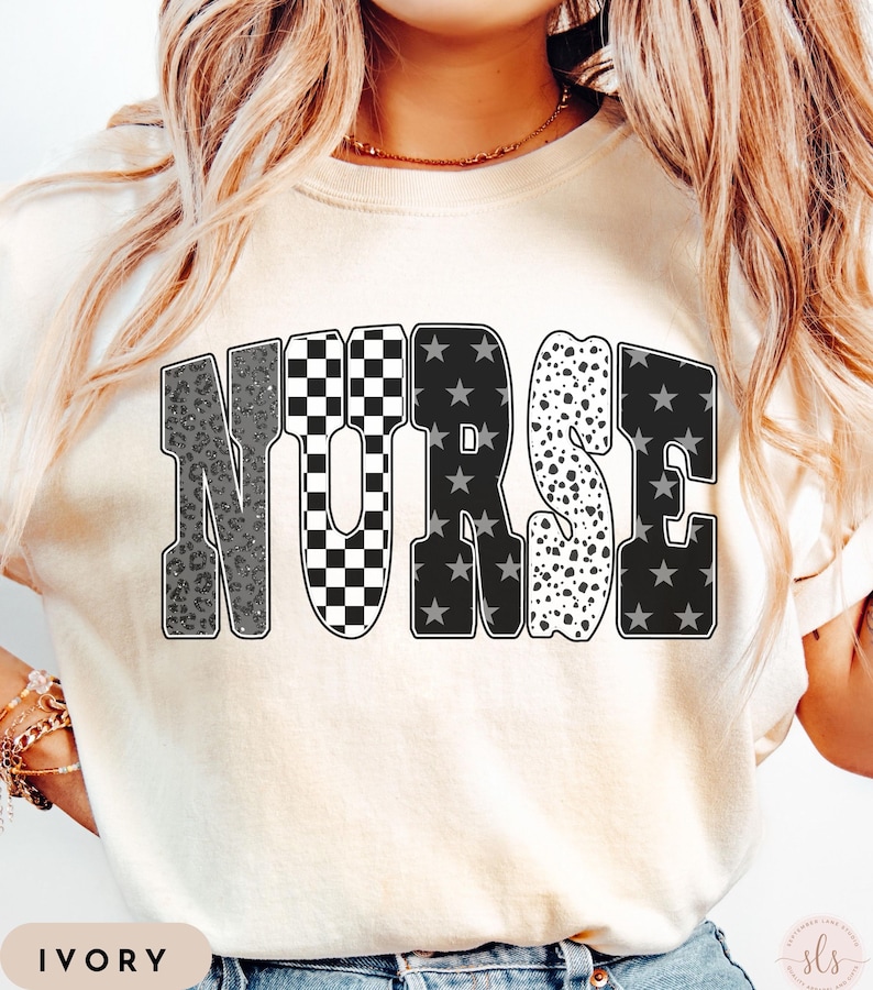 May include: Ivory-colored t-shirt with the word "NURSE" in a bold, multi-patterned design. The letters feature leopard print, checkered, star, and polka dot patterns. The word "IVORY" is printed at the bottom of the shirt.