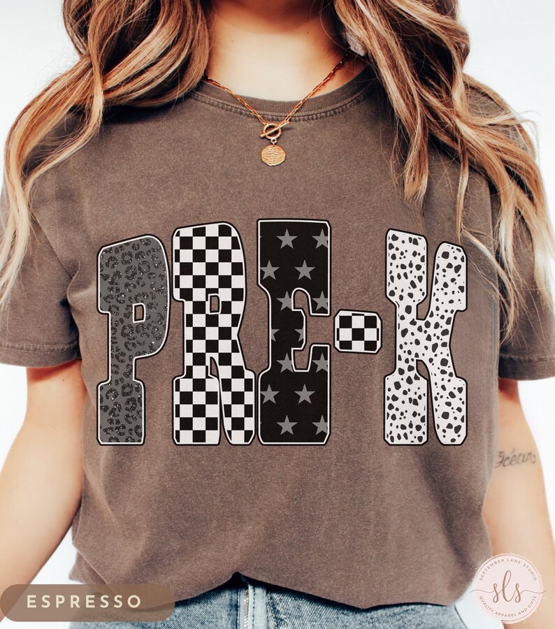 K&ouml;nnte beinhalten: Espressofarbenes T-Shirt mit dem Wort "PRE-K" in einem auff&auml;lligen, gemusterten Design. Die Buchstaben zeigen Leopardenmuster, ein schwarz-wei&szlig;es Schachbrettmuster, Sterne und Dalmatinerflecken. Eine goldene Halskette ist sichtbar.