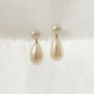 May include: A pair of elegant pearl drop earrings. Each earring features a small, round pearl stud connected to a larger, teardrop-shaped pearl. The earrings have gold-colored metal accents and hang against a white background.