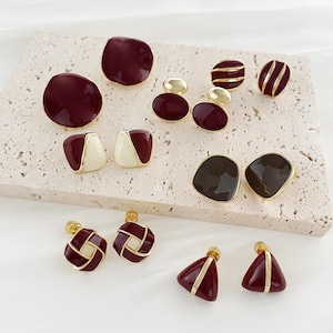 Puede incluir: Surtido de 10 pares de pendientes de tono dorado con diversas formas geométricas y esmalte burdeos, blanco y negro.