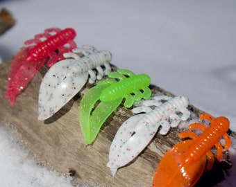 May include: Five different colored plastic fishing lures. The lures are shaped like crawfish and have a segmented body. The colors are red, white, green, white with red and orange.