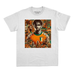 May include: White t-shirt with a graphic of a person in an orange and green jersey with the Ivory Coast flag. The graphic has a patterned background. The text "AFRIK CULTURE CLOTHING" is at the top.