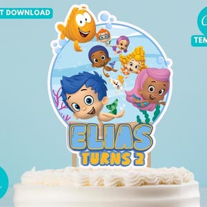 May include: A cake topper with Bubble Guppies characters, the text "ELIAS TURNS 2", and the words "INSTANT DOWNLOAD" and "Canva TEMPLATE". The topper is on a white frosted cake. The background is light blue.