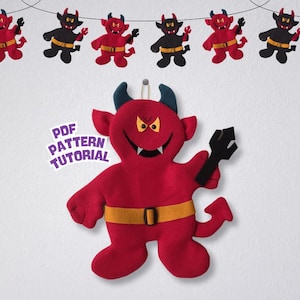 Puede incluir: Un diablo rojo de peluche con cuernos azules y cinturón amarillo, sosteniendo un tridente negro. Una pancarta de figuras de diablo cuelga arriba. Incluye el texto "PDF PATTERN TUTORIAL".
