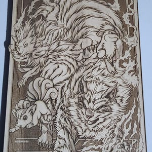 May include: Wooden engraved card featuring a detailed illustration of several fantasy creatures, including a large, fiery wolf-like figure and smaller, fox-like characters. The word "BASIC" is at the top. The card has a light brown color.