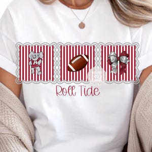 Könnte beinhalten: Weißes T-Shirt mit einem Design, das einen Elefanten, einen Football und Schleifen zeigt. Das Design ist vor einem rot-weiß gestreiften Hintergrund platziert. Die Worte "Roll Tide" sind in einer Schreibschrift unter dem Design geschrieben.