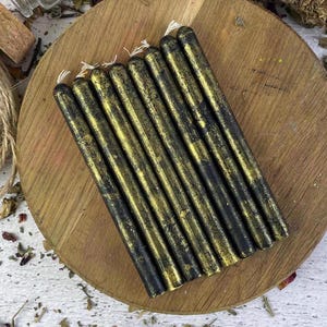May include: A bundle of black and gold taper candles. The candles have a distressed, textured finish.