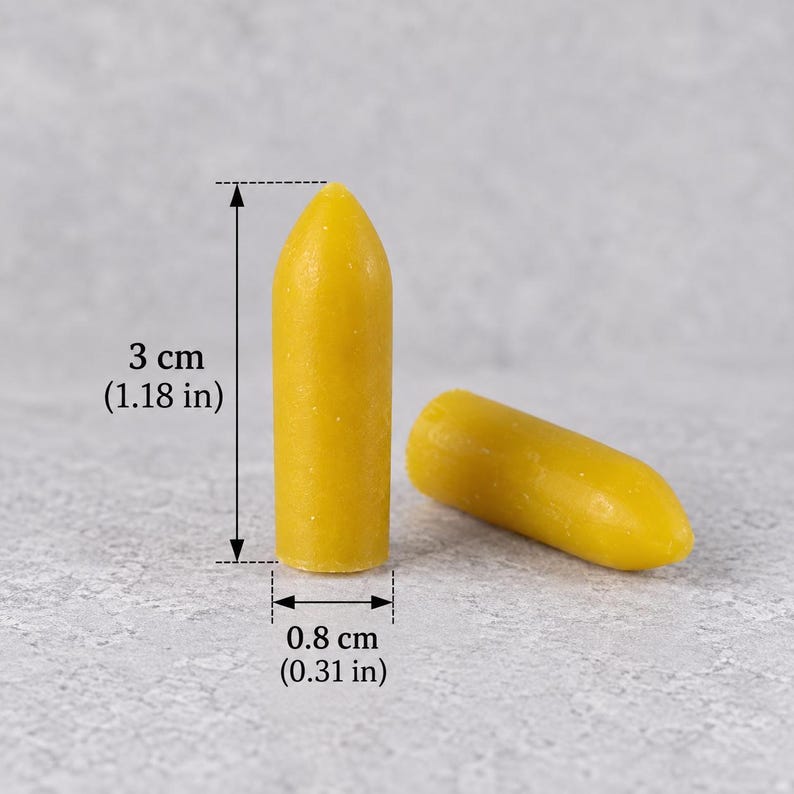 Two yellow suppository-shaped wax samples showing dimensions of 3 cm (1.18 in) tall and 0.8 cm (0.31 in) wide for a reusable silicone suppository mold and DIY home crafting