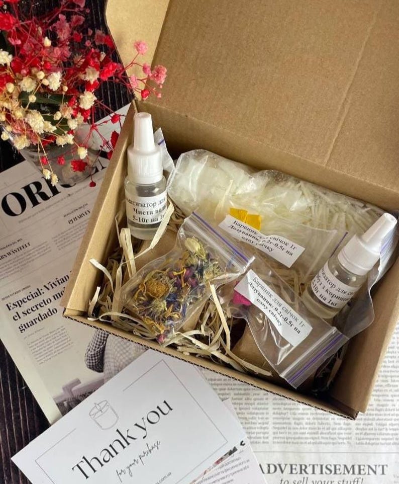 Top view of soy candle making kit components in a box, including essential oils, wax, flowers, and colorants in clear labeled pouches, ideal for DIY natural candles.