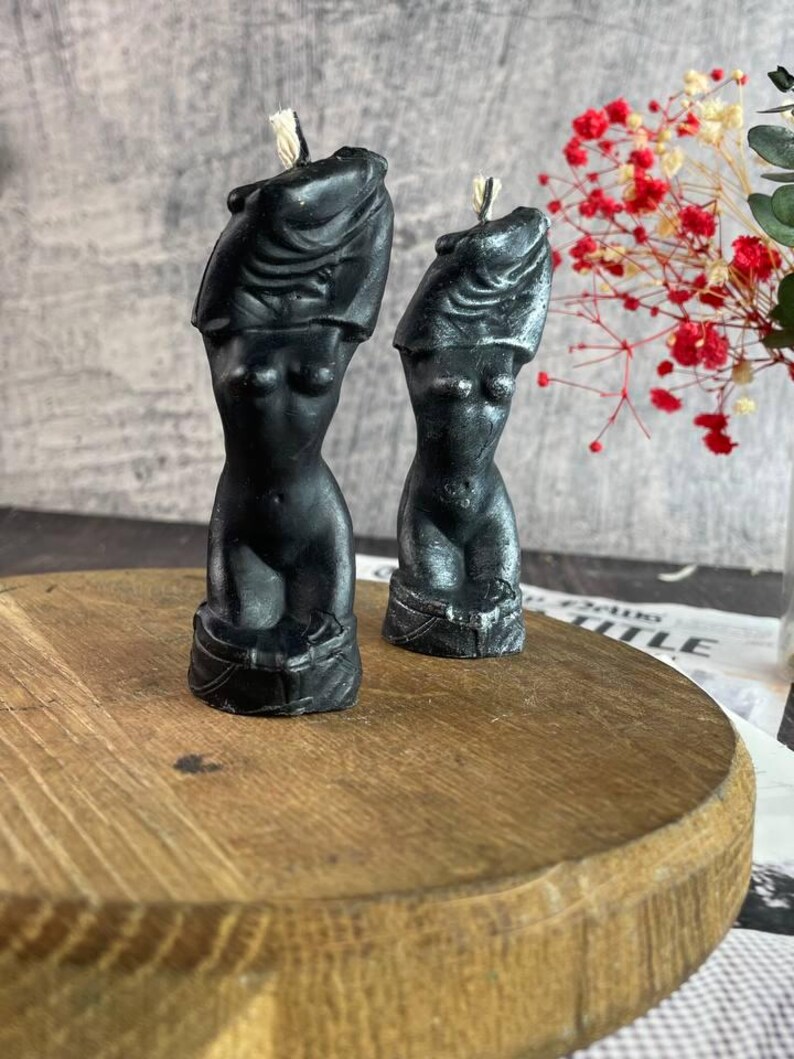 A pair of handcrafted black female body candles with a sleek silver shimmer finish