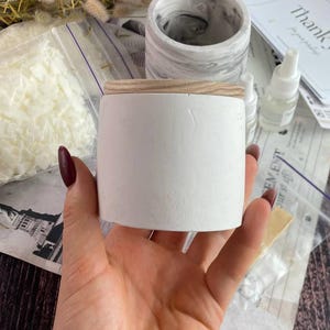 Minimalist white candle jar in hand, part of candle making kit.