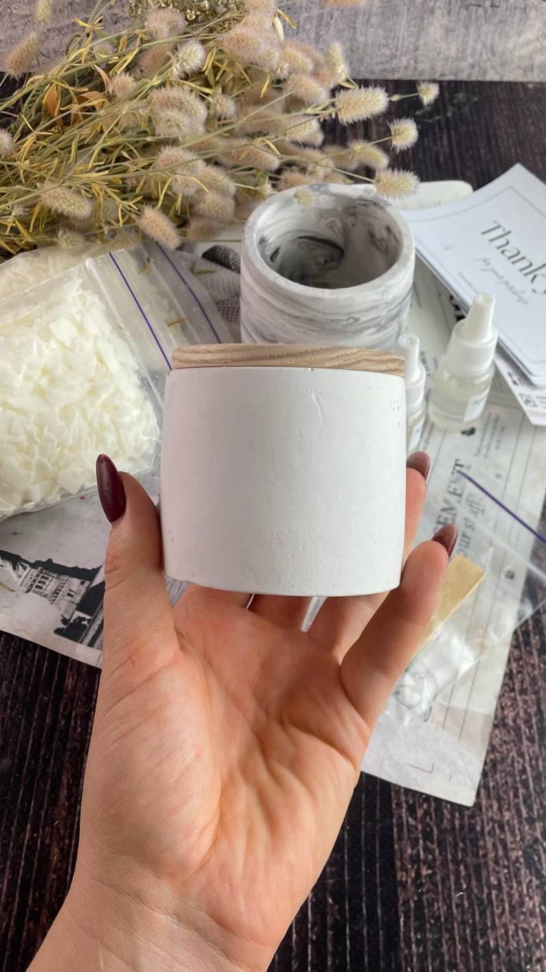Minimalist white candle jar in hand, part of candle making kit.