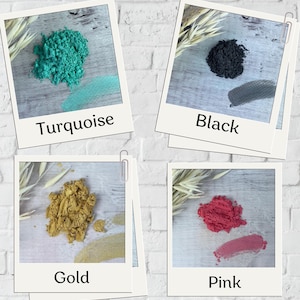 Può includere: Quattro piccoli contenitori di pigmenti in polvere colorati. I colori sono turchese, nero, oro e rosa.
