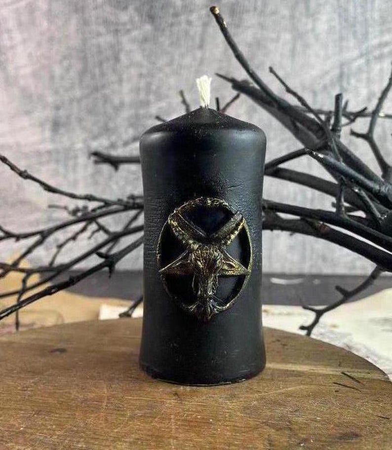 Handmade black beeswax spell candle with detailed Baphomet carving