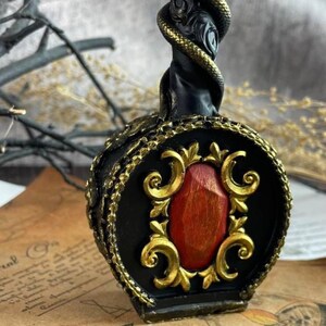 Detailed view of the ornamental golden scrollwork and central red stone-like wax accent