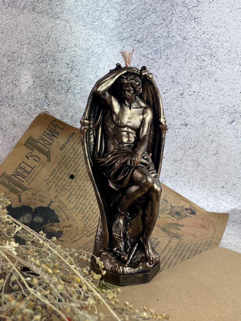 Bronze Lucifer-shaped candle burning next to tarot cards and crystals on a dark wooden surface, creating a mystical and dramatic atmosphere.