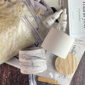Wooden wick and metal holder set included in DIY candle making kit.
