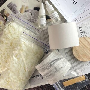 Flat lay of eco-friendly soy wax flakes, oils, and marble jars for candle crafting.