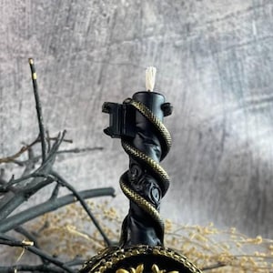 Close-up of the black candle’s detailed serpent design wrapping the vertical handle