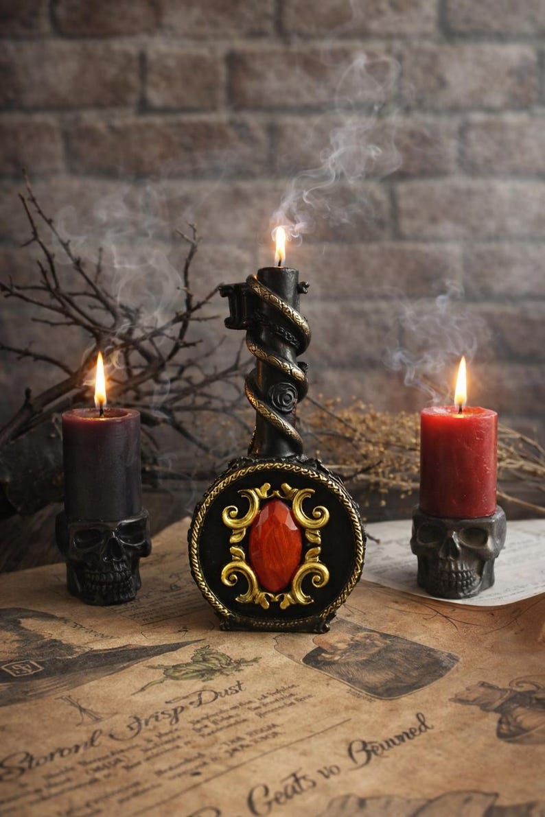 Black ritual candle shaped like a mystical key with ornate red gemstone detail, surrounded by burning candles on skull holders and smoky atmospheric altar setting.