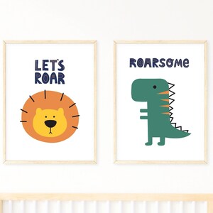 Pode incluir: Duas impressões emolduradas com fundo branco. A impressão à esquerda apresenta um leão de desenho animado com o texto "Let's Roar". A impressão à direita apresenta um dinossauro de desenho animado com o texto "Roar-some".