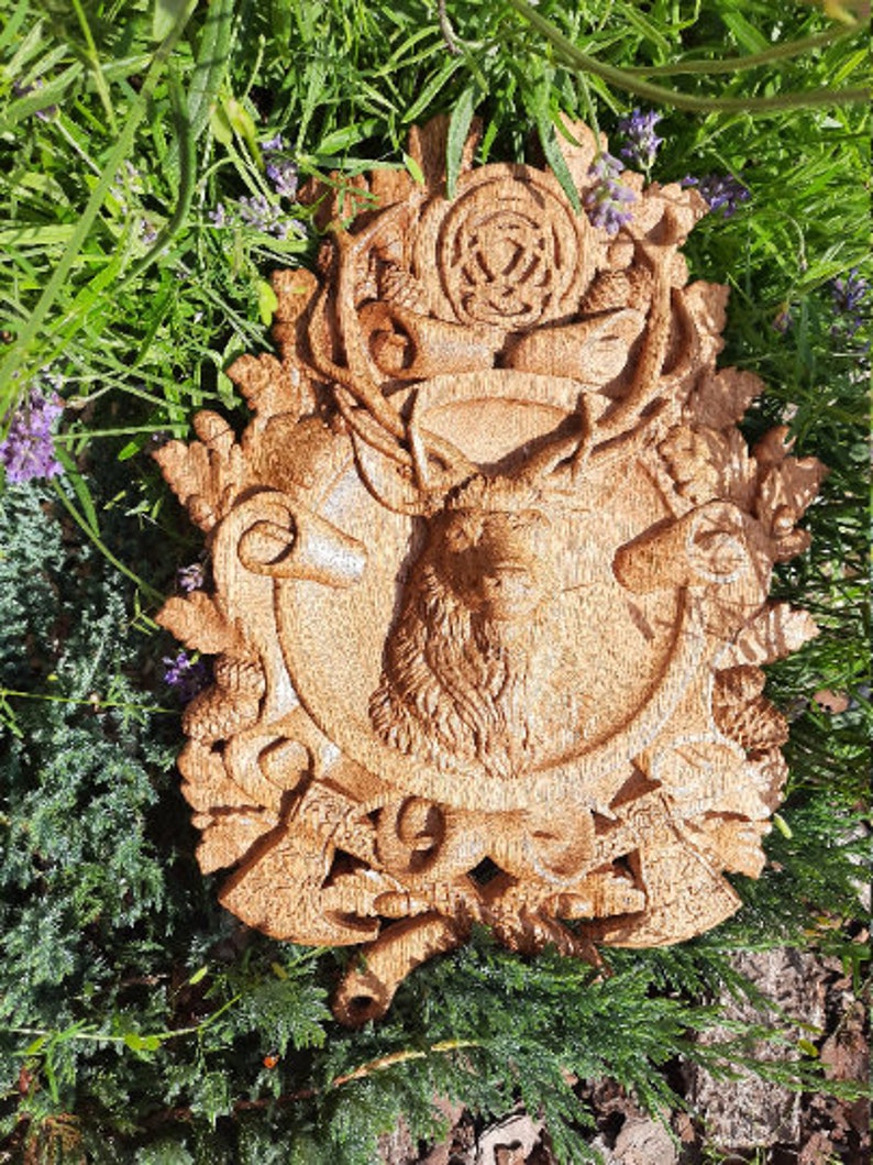 May include: A wooden wall plaque with a carved stag head surrounded by a wreath of leaves, acorns, and other woodland motifs. The plaque is painted in a warm brown color.