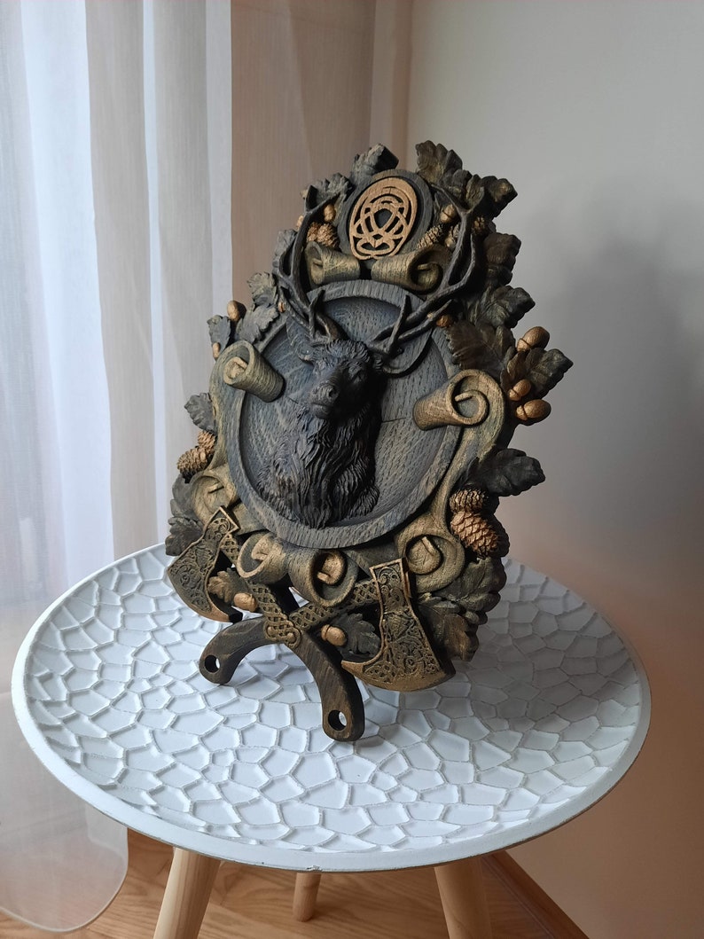 May include: A wooden wall plaque with a carved deer head, two axes, and a Celtic knot design. The plaque is painted in shades of brown and gold.