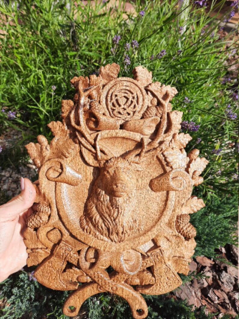 May include: A wooden wall plaque with a carved stag head, surrounded by intricate details like leaves, acorns, and a Celtic knot. The plaque is painted in a warm brown color.