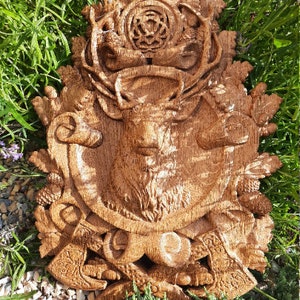 May include: A detailed wooden carving of a stag's head with antlers, surrounded by intricate foliage and a Celtic knot design. The carving is mounted on a wooden plaque and has a rich brown color.