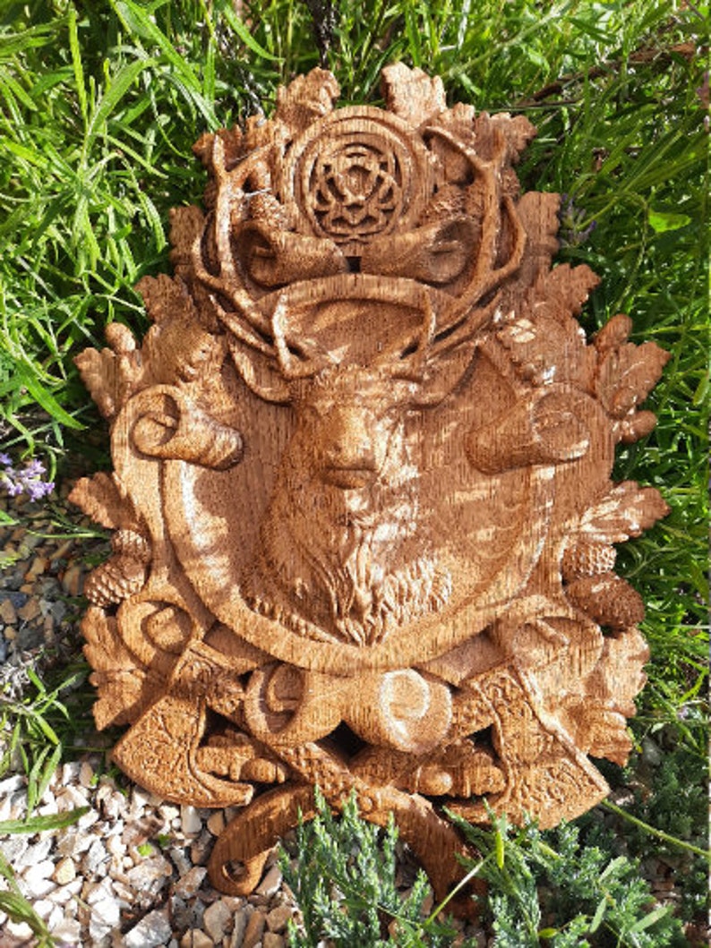 May include: A detailed wooden carving of a stag's head with antlers, surrounded by intricate foliage and a Celtic knot design. The carving is mounted on a wooden plaque and has a rich brown color.