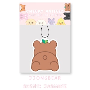 May include: A brown bear-shaped car air freshener with a green leaf on its head. The air freshener is hanging from a string and has the text "CHEEKY ANITEEZ CAR AIR FRESHENER" and "JJONGBEAR SCENT: JASMINE" printed on it.
