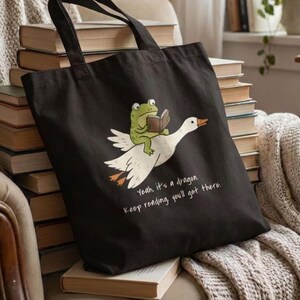 Frog reading a book and Riding Goose Tote Bag, funny bookish gift for romantasy reader and dragon lovers. Yes, it's a dragon, keep reading