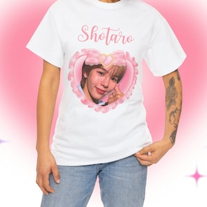 May include: White t-shirt with a pink heart design featuring a portrait of a person with the text "Shotaro" above the heart.