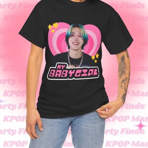 May include: Black t-shirt with a pink heart graphic featuring a person with blue and green hair. The text "MY BABYEYRL" is printed in pink letters on the shirt.